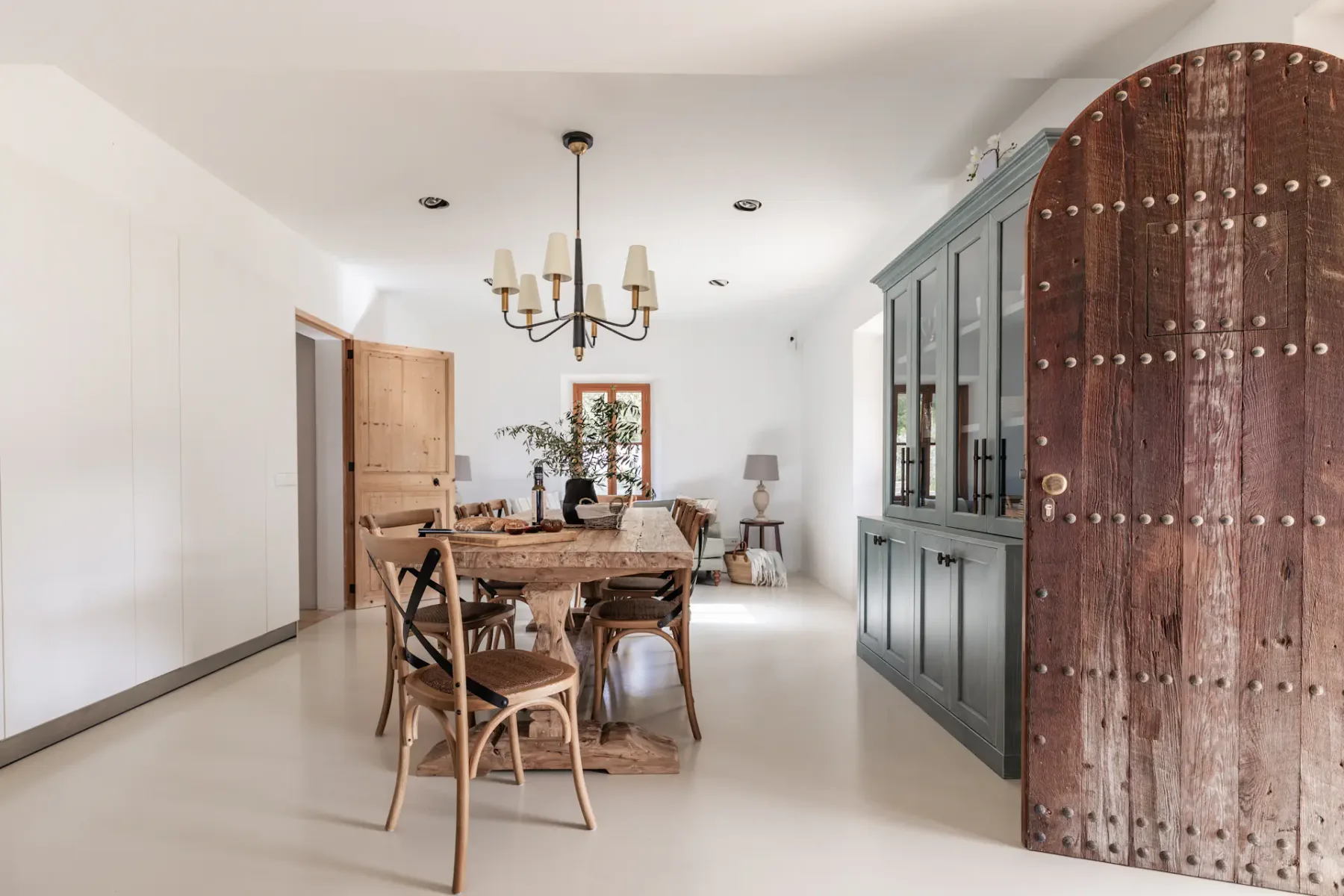 A dining area with a wooden table and chairs beside a dark cabinet.