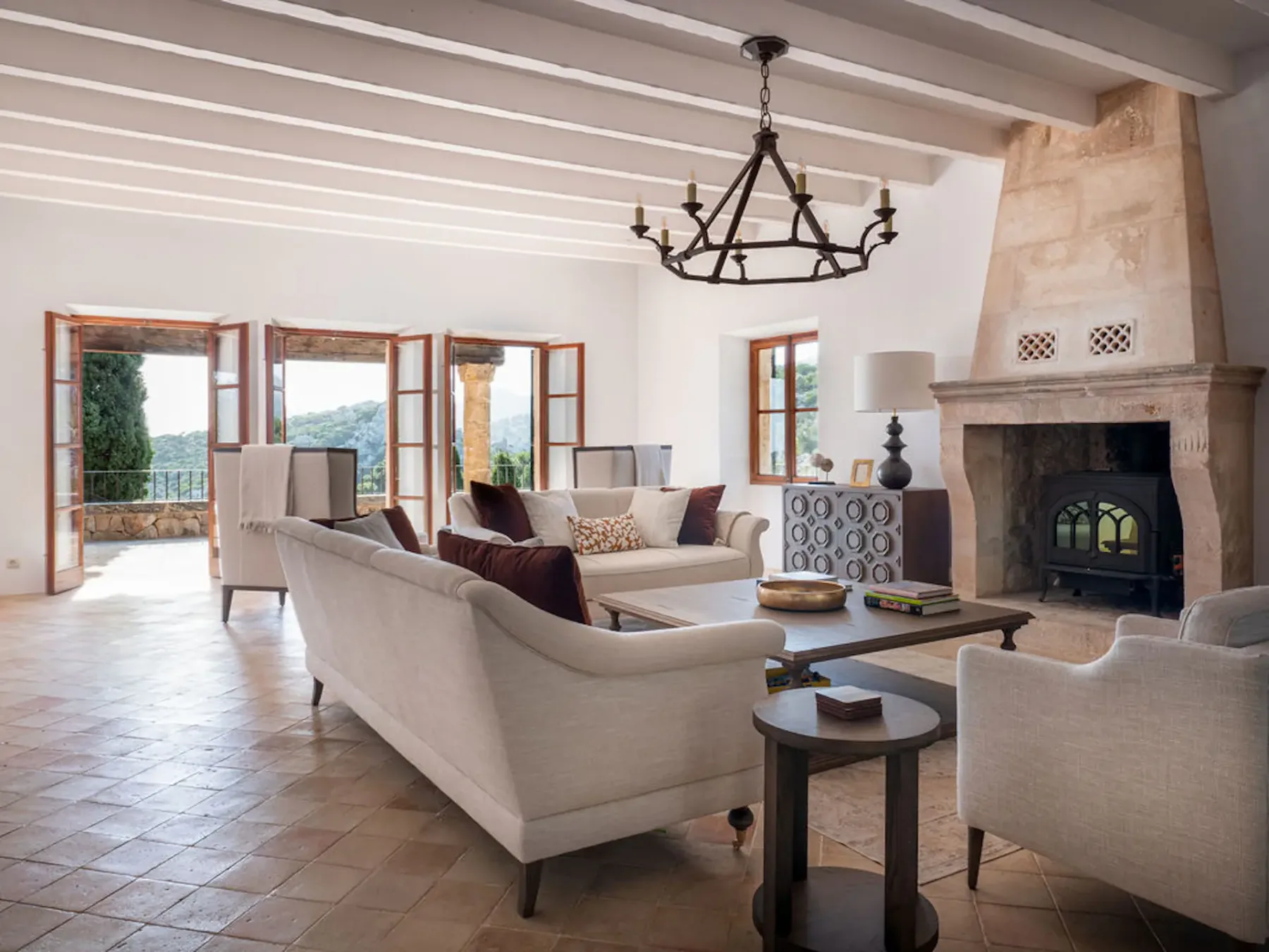 A bright living room with sofas arranged around a coffee table and fireplace.