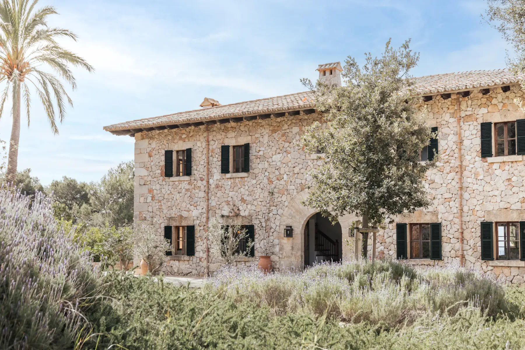 A stone house facade with dark windows and an arched entrance.