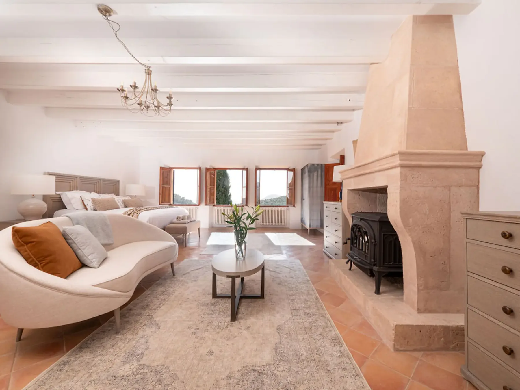A bright living room with curved seating and a large fireplace.
