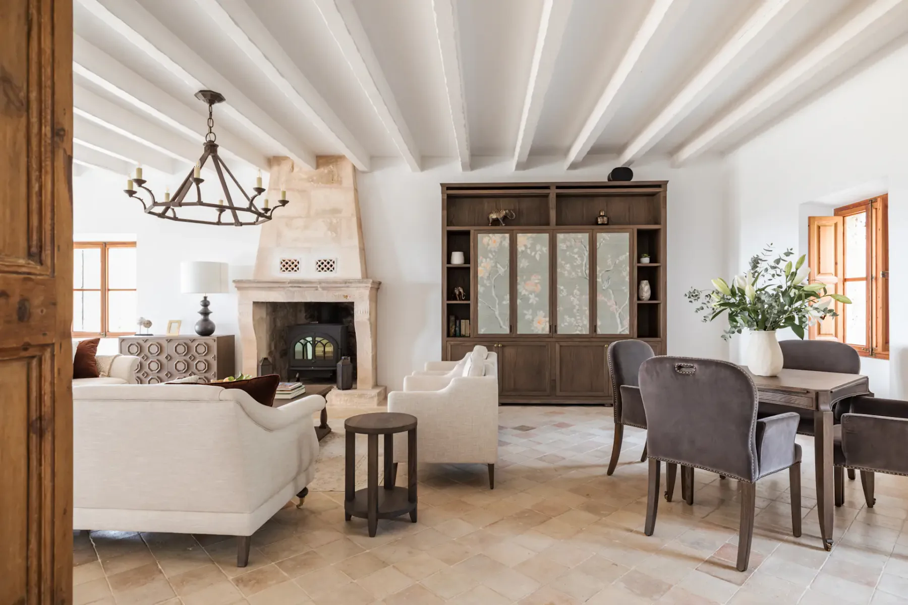 A bright living room with seating, a fireplace, and a dining table.