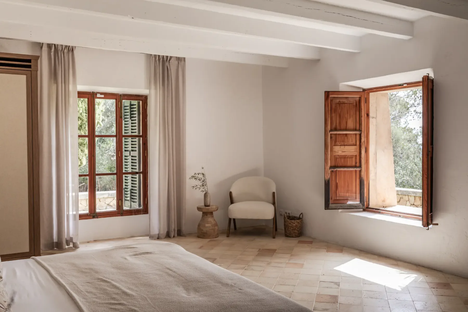 A bright bedroom with a bed and two windows, one open.