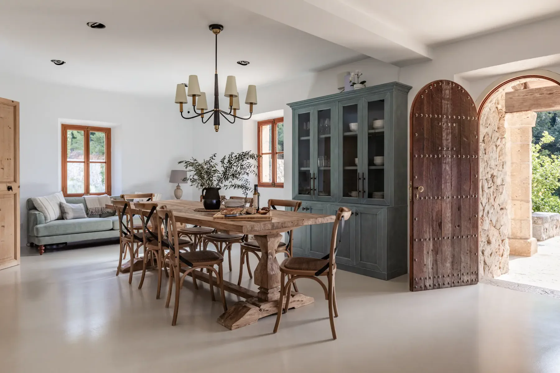 A dining area with a long wooden table, chairs, and a dark cabinet.