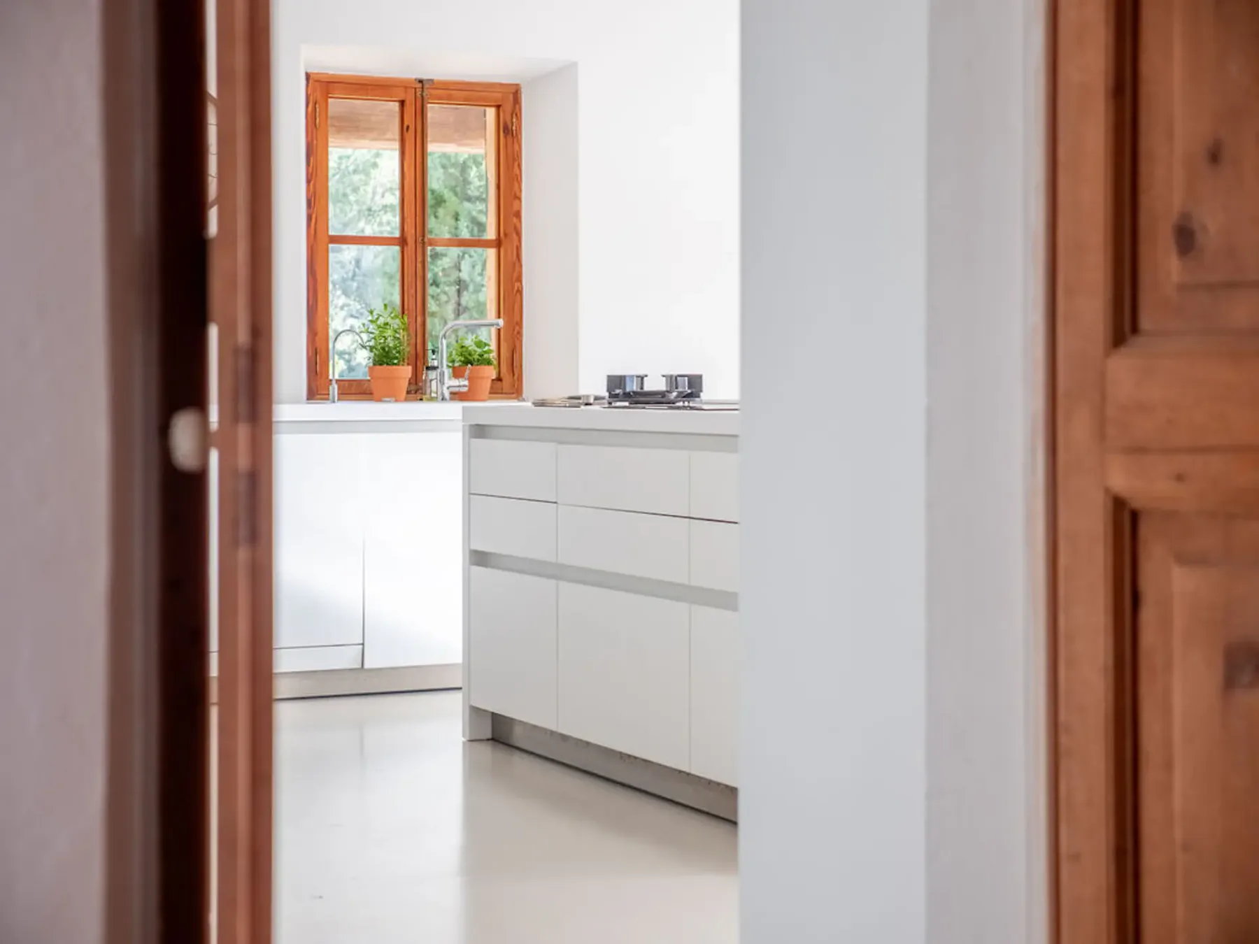A bright kitchen with white cabinets and a wooden-framed window.