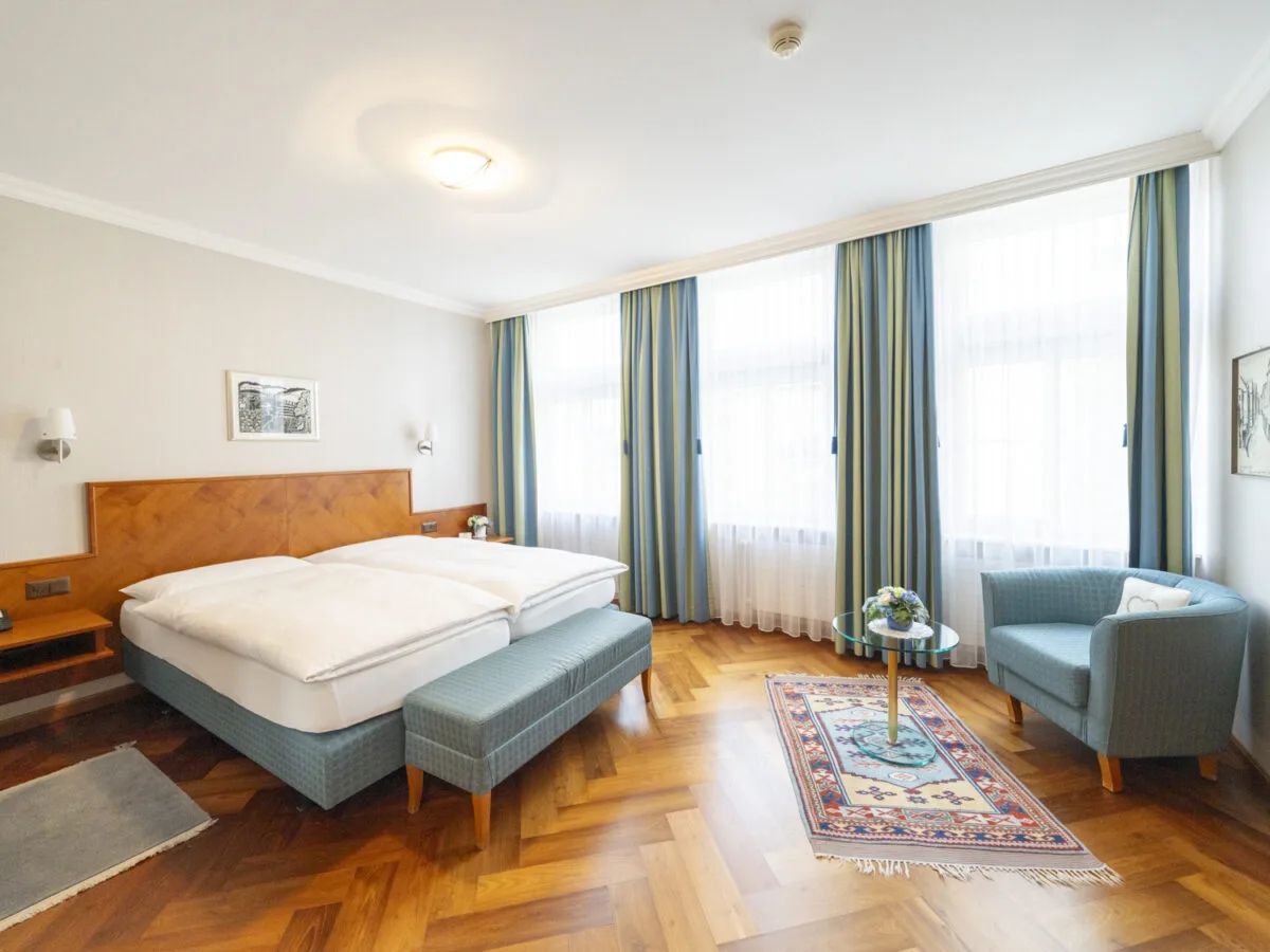 Classic Double Room with a double bed, blue bench and window-side chair.