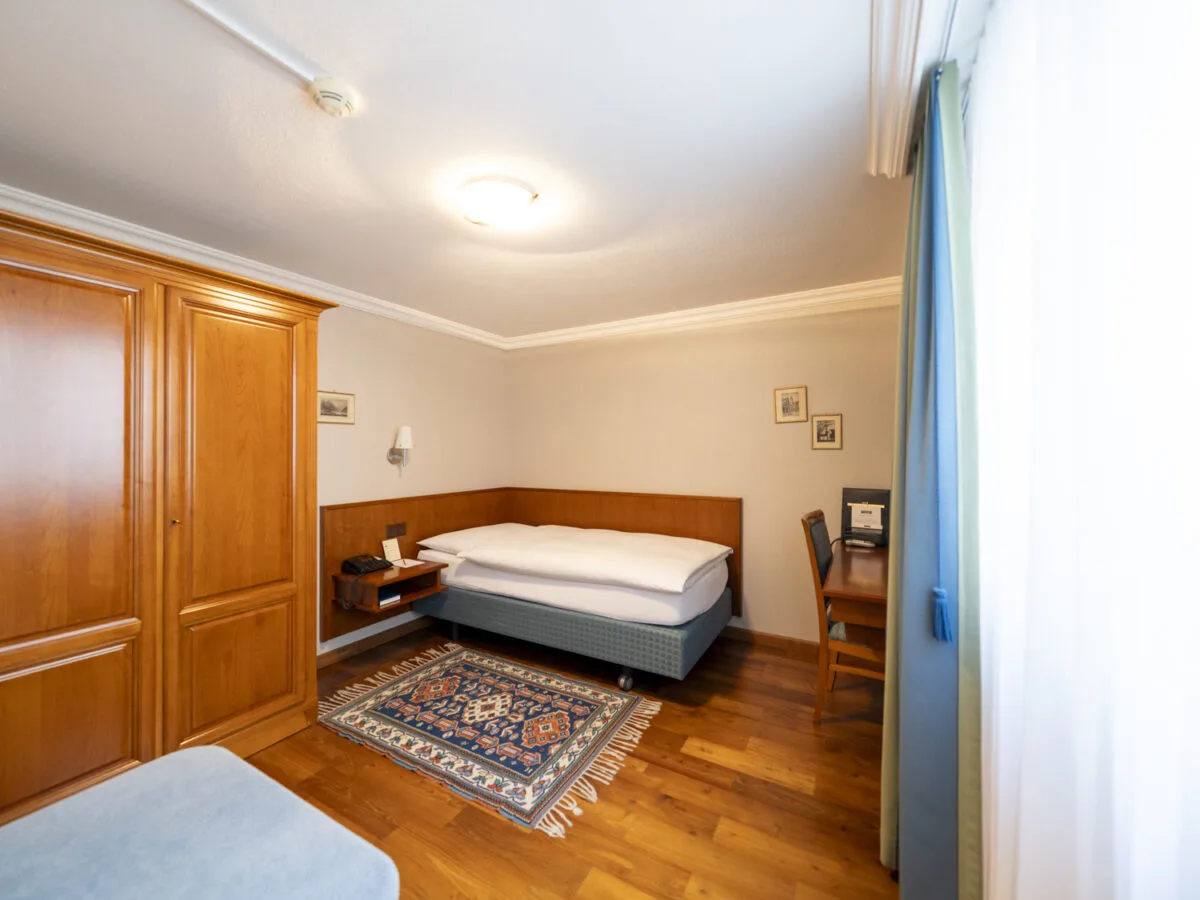 Single Room with a wooden wardrobe, desk and parquet flooring.