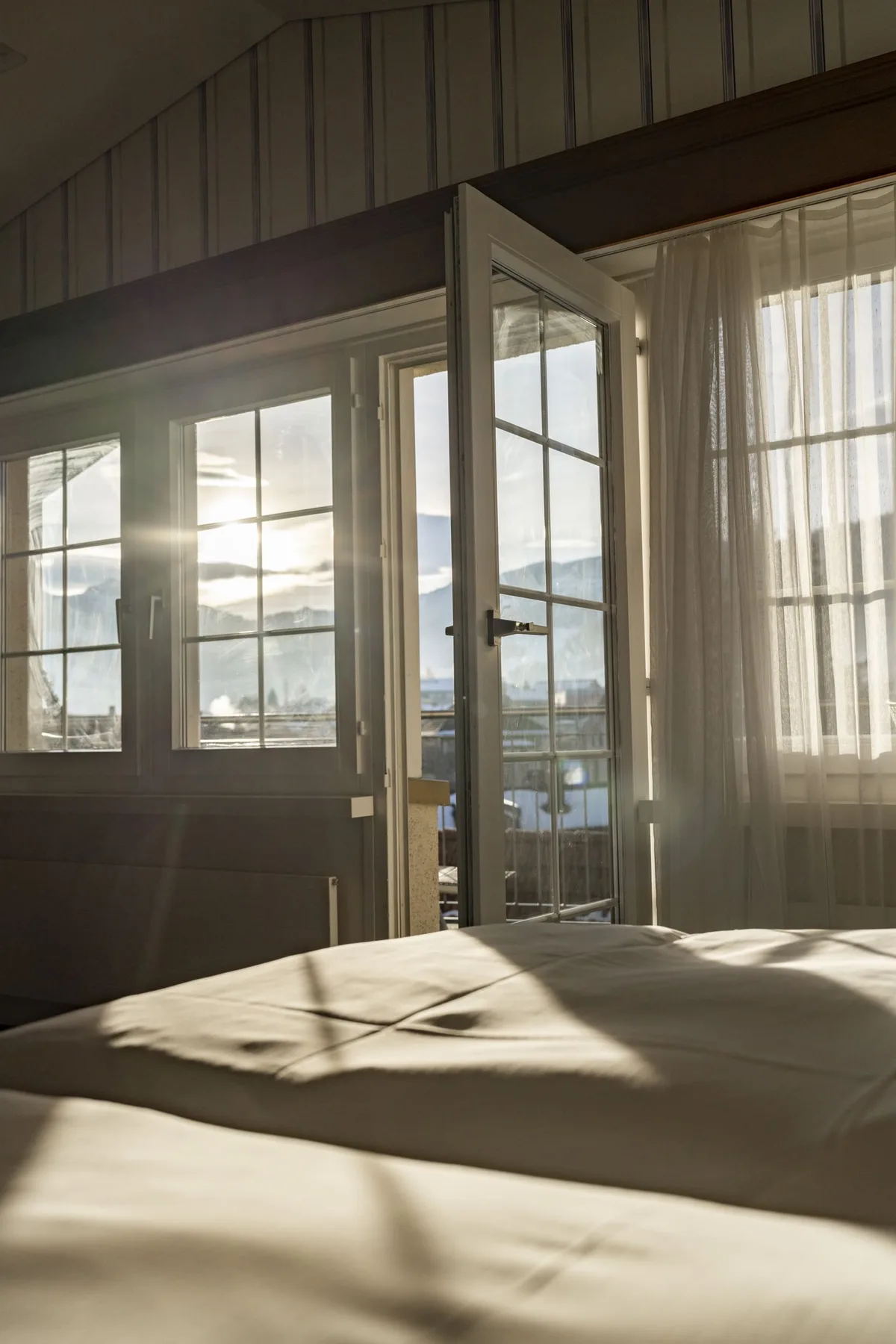View from the Panorama Junior Suite bed through the balcony door to the winter landscape.