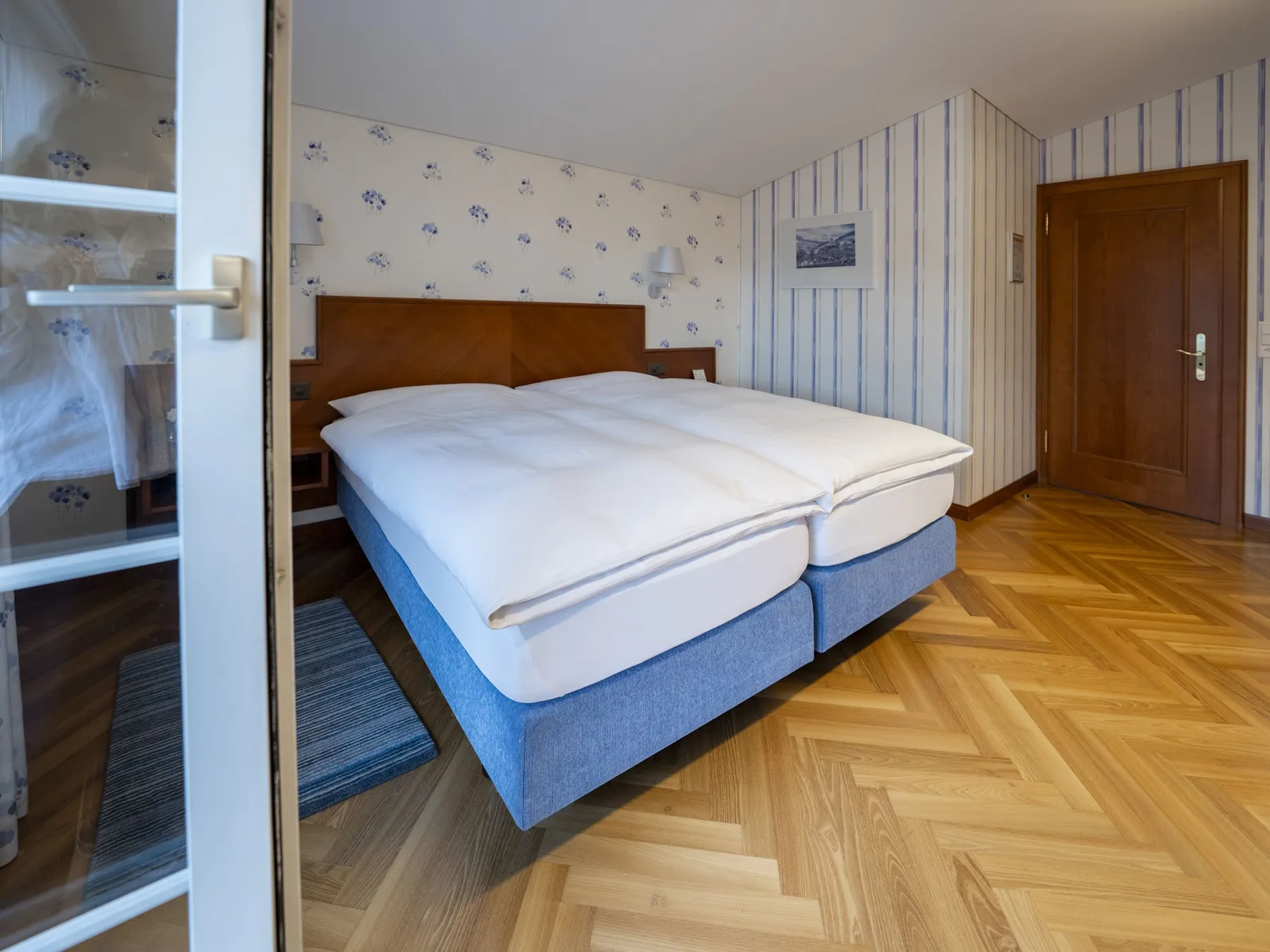 Panorama Junior Suite double bed with patterned wallpaper and bedside tables.