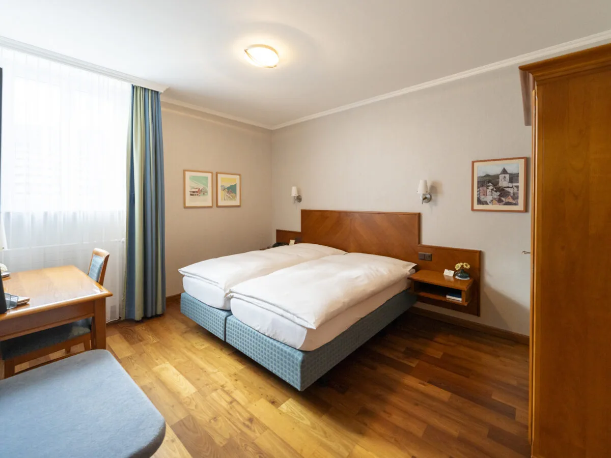 Basic Double Room with a double bed, wood flooring and wooden furniture.