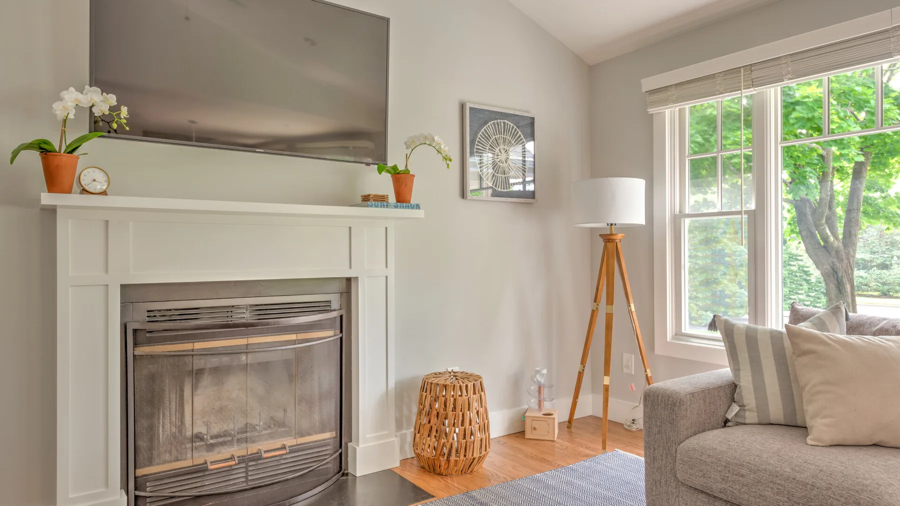 A bright living room with a fireplace, television, and large windows.