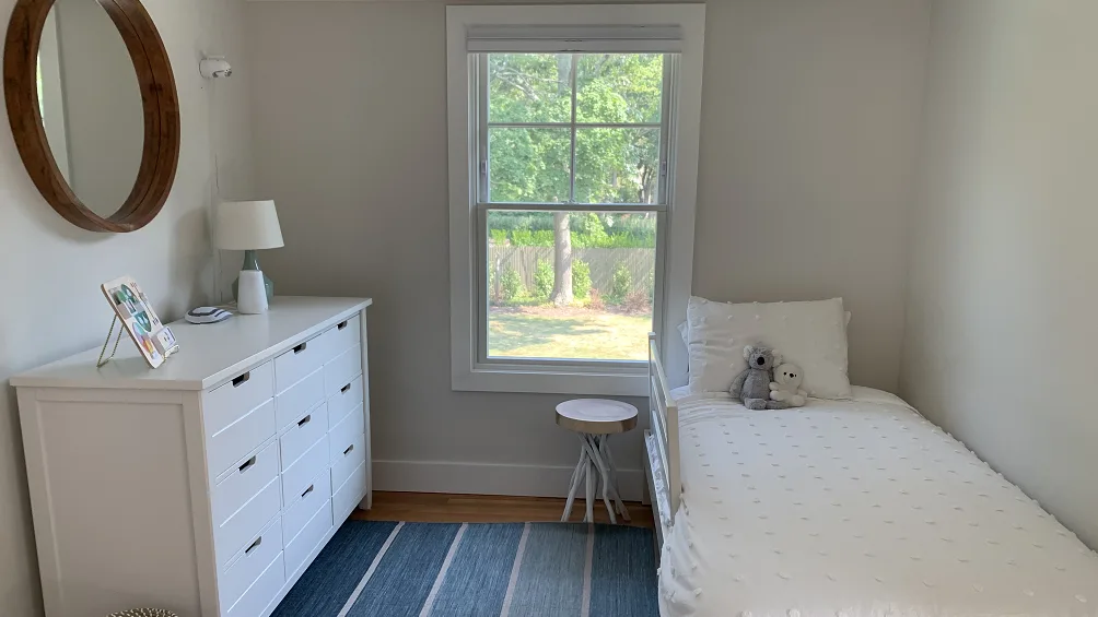 A bright bedroom with a single bed beside a window.