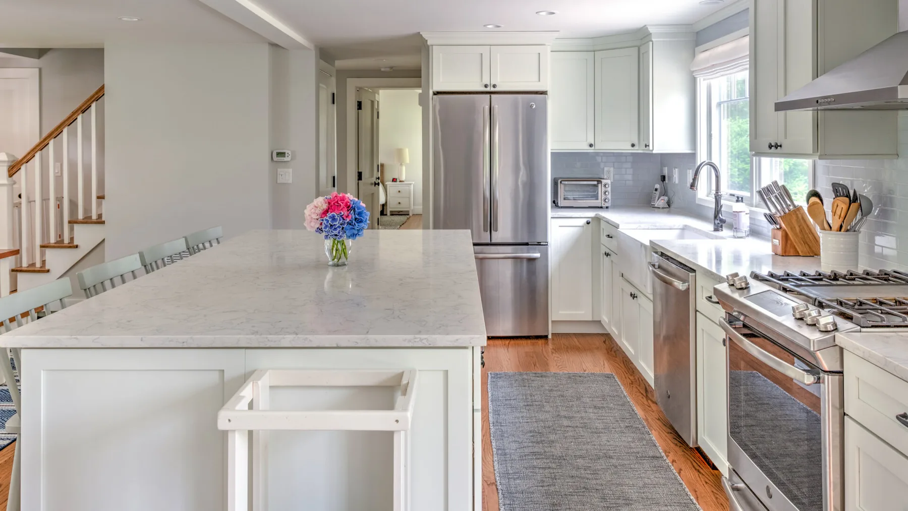 A bright kitchen with white cabinetry, stainless steel appliances, and a large island.