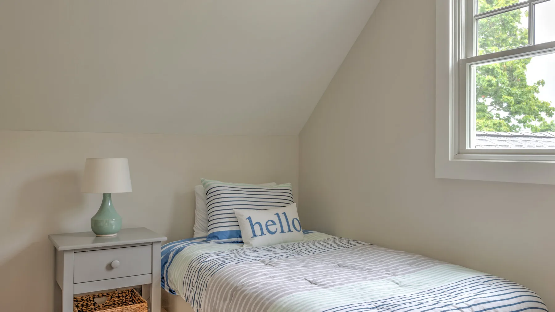 A bedroom with a bed, bedside table, and window.