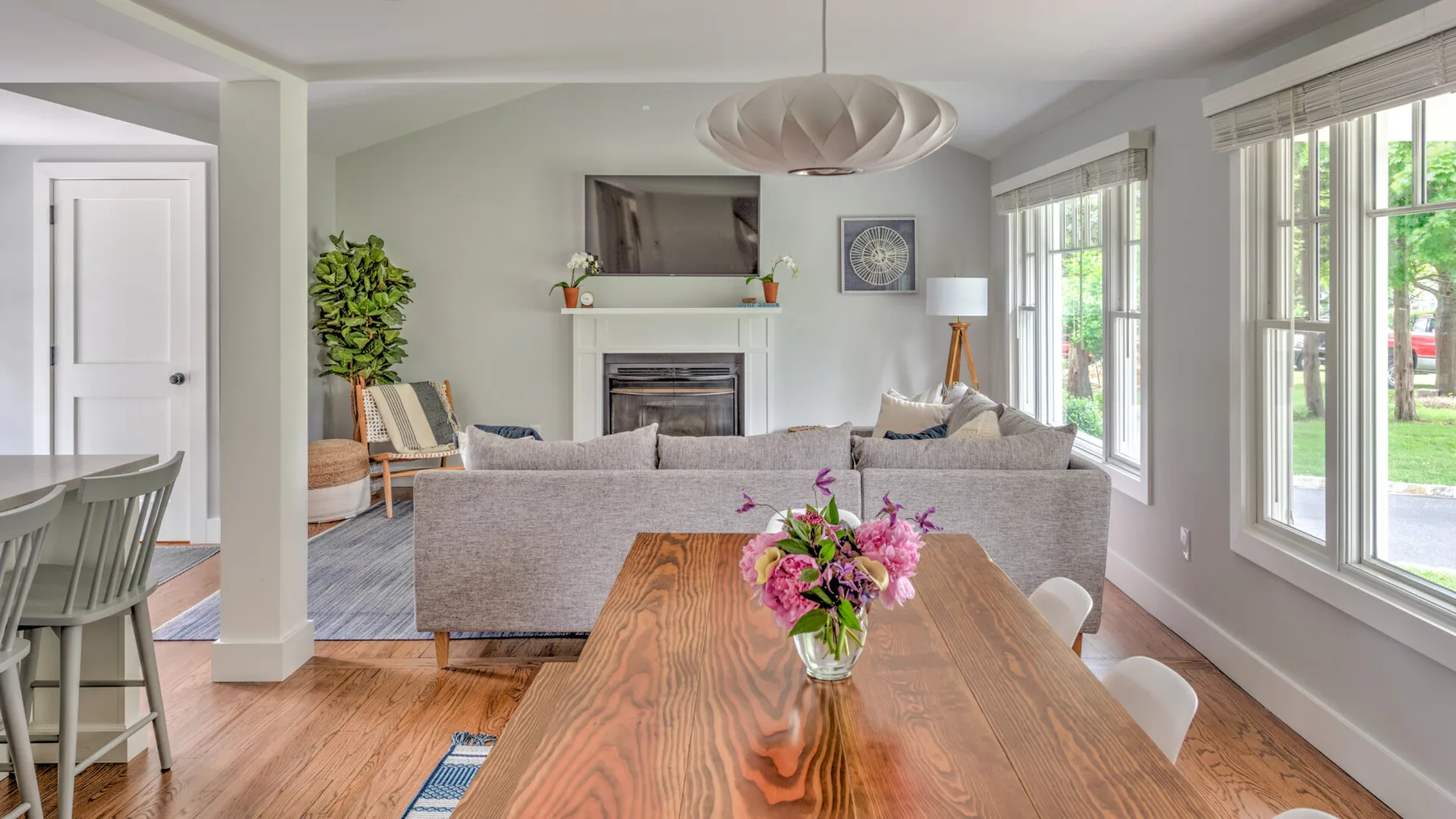 A bright living room with seating around a fireplace and a wooden dining table.