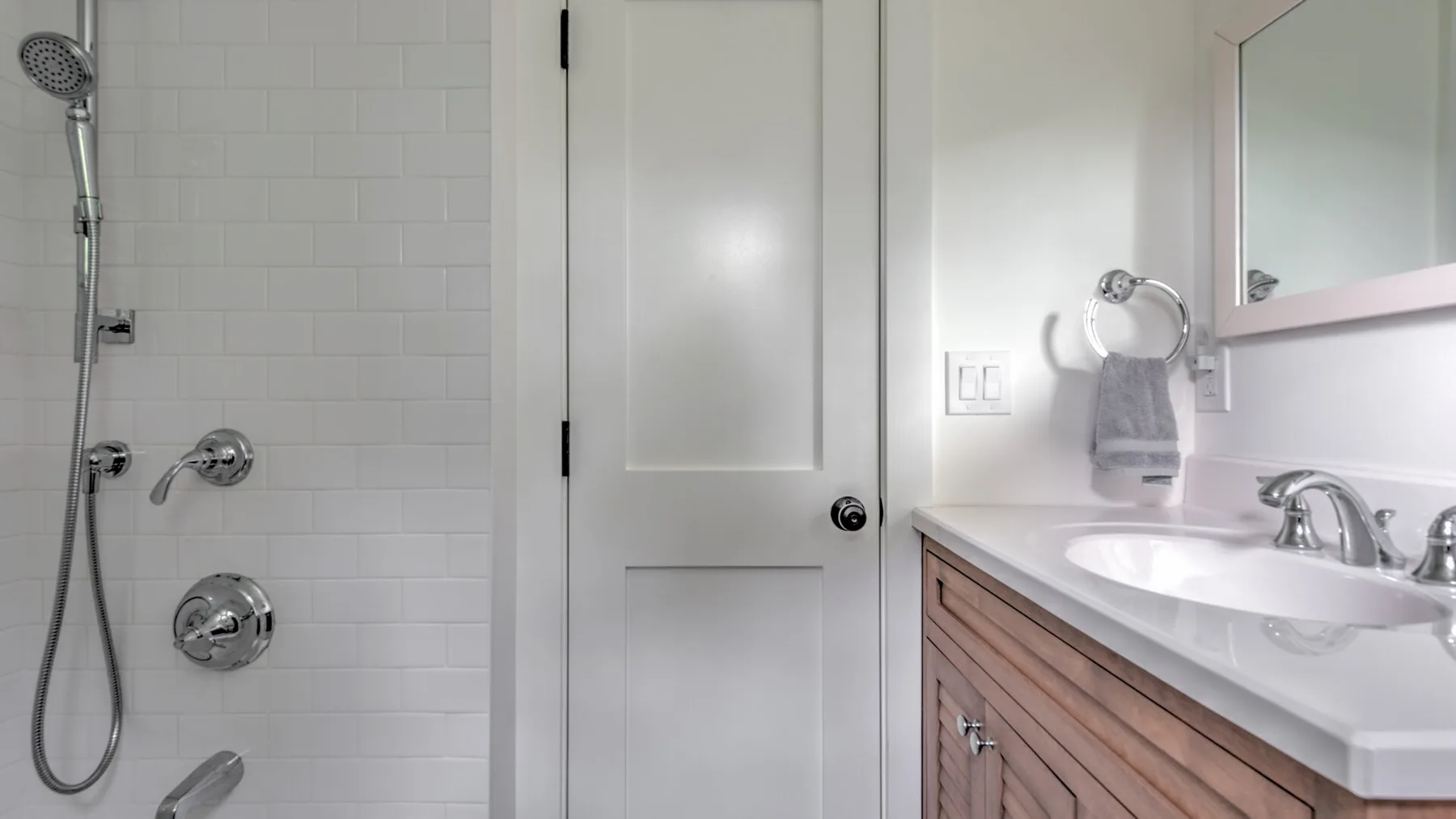 A bathroom with a shower, sink, and wooden vanity.