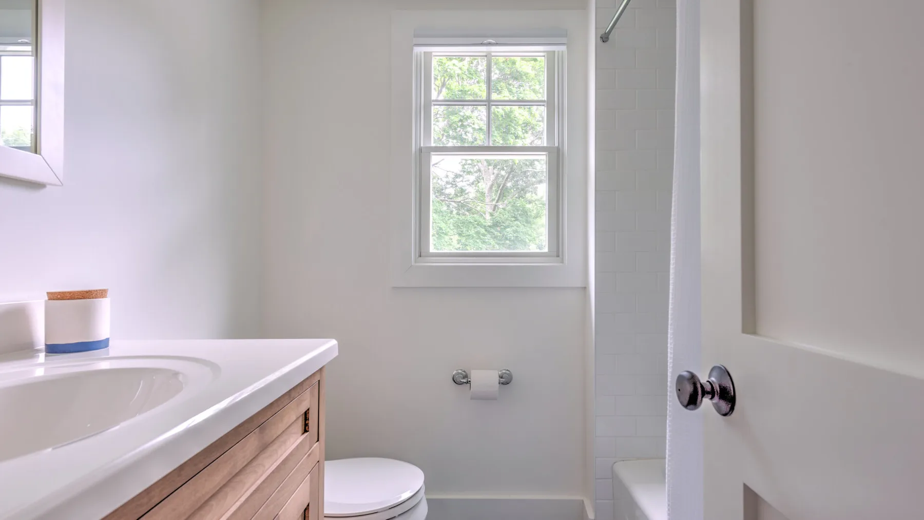 A bathroom with a vanity, toilet, and window.