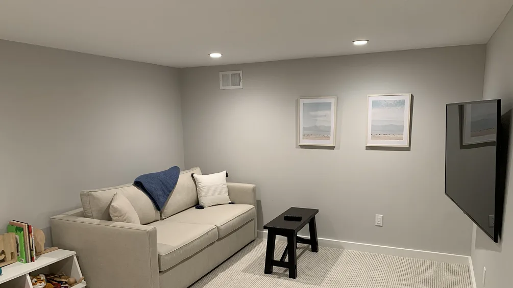 A living room with seating, a small table, and framed pictures on the wall.