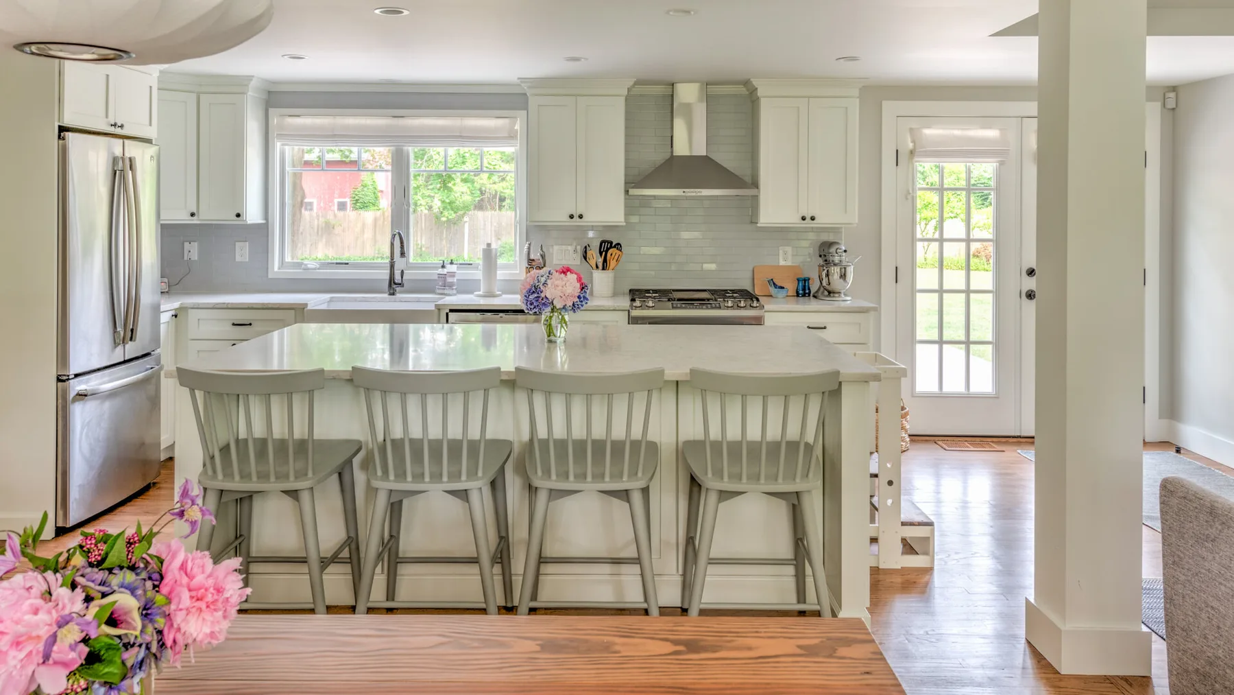 A bright kitchen with a large island and seating beneath pendant lights.