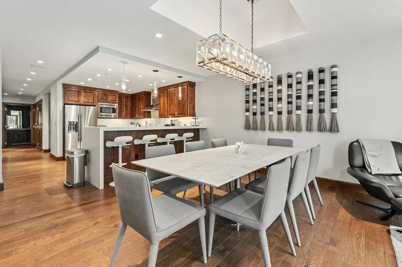 A dining area with a large table and an open kitchen beyond it.