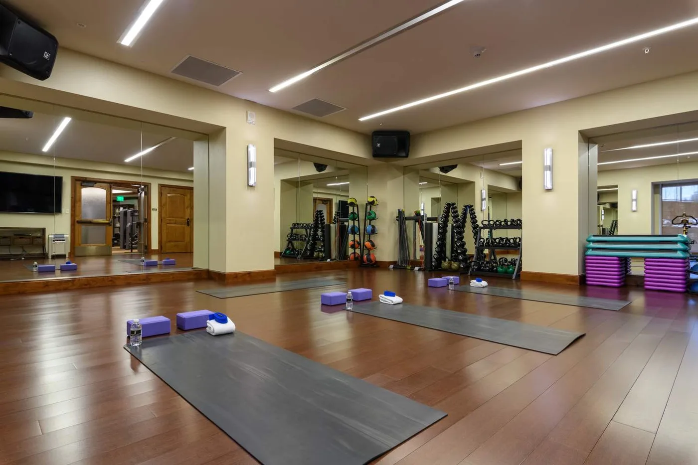 A fitness studio with mirrored walls, exercise mats, and stacked step platforms.