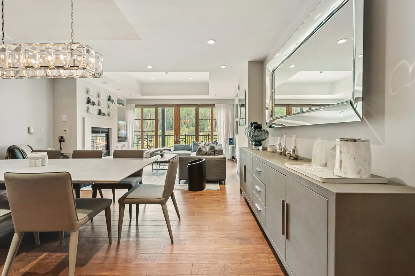 A bright open-plan dining and living room with large windows and a long sideboard.