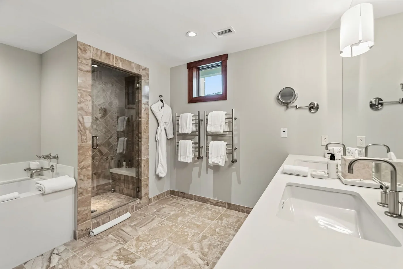 A bathroom with a glass shower, a bathtub, and a wide sink counter.