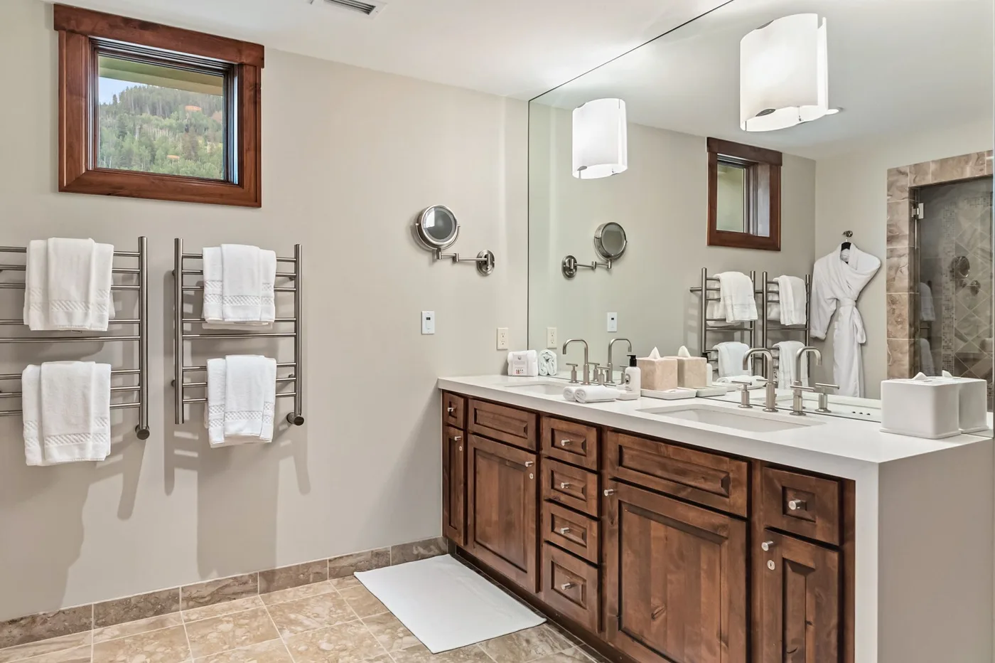 A bathroom with a wood vanity, sinks, and wall-mounted towel racks.