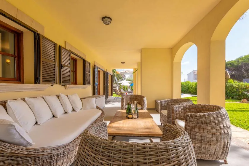 Una zona de estar exterior cubierta con muebles de mimbre y una mesa de madera.