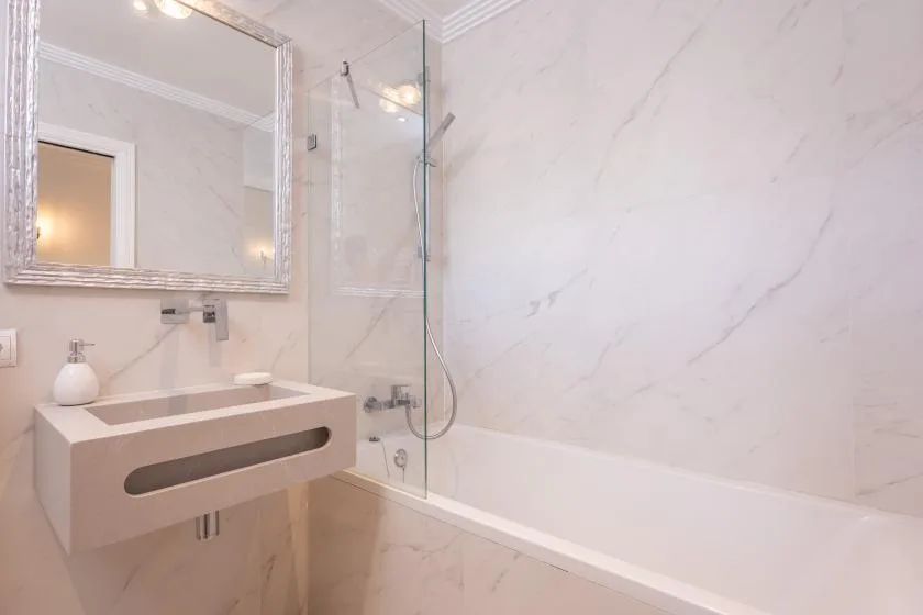 Un baño con bañera, ducha y lavabo suspendido.