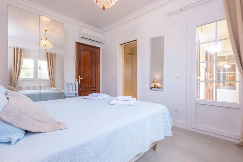 Un dormitorio luminoso con una cama bien hecha y un armario con espejo alto.