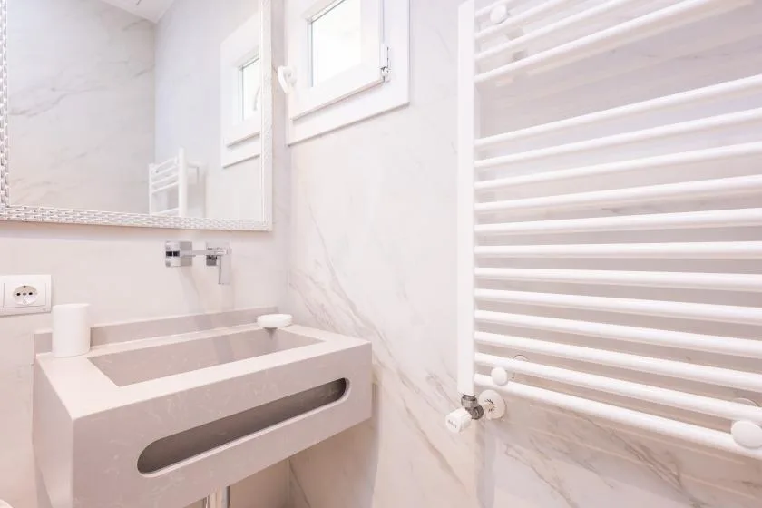 Un baño luminoso con un lavabo debajo de un espejo de pared.