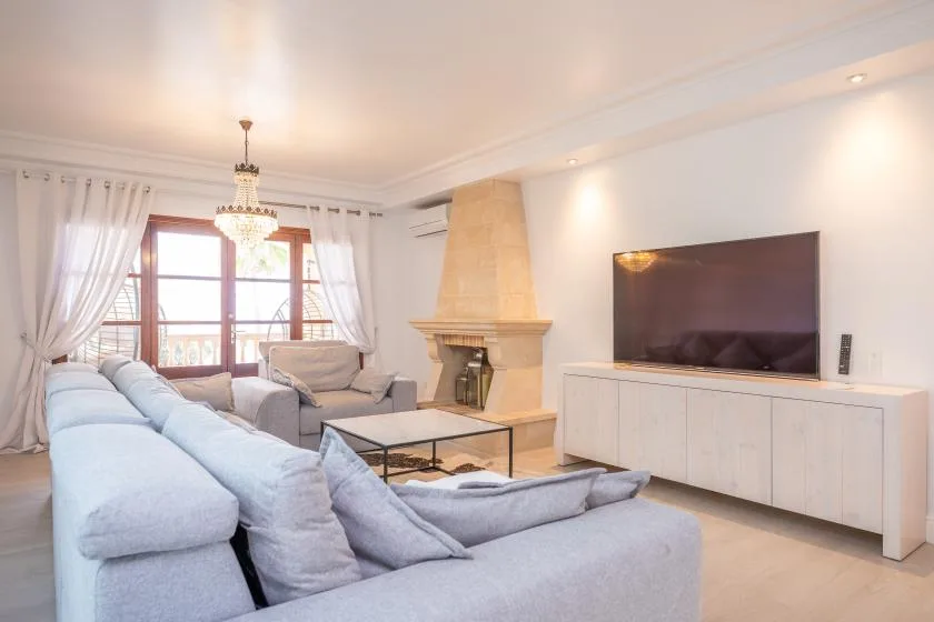 Una sala luminosa con asientos, un televisor y una chimenea.
