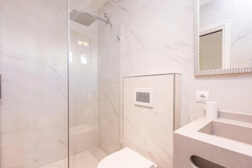 Un baño luminoso con una ducha de vidrio y un lavabo.