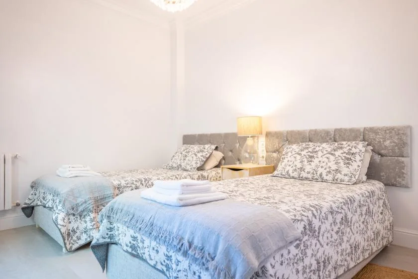 Un dormitorio con dos camas, ropa de cama estampada y una lámpara entre ellas.