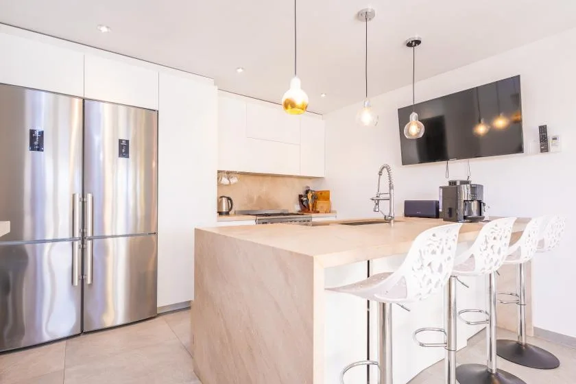 Una cocina moderna y luminosa con una isla grande y asientos blancos.