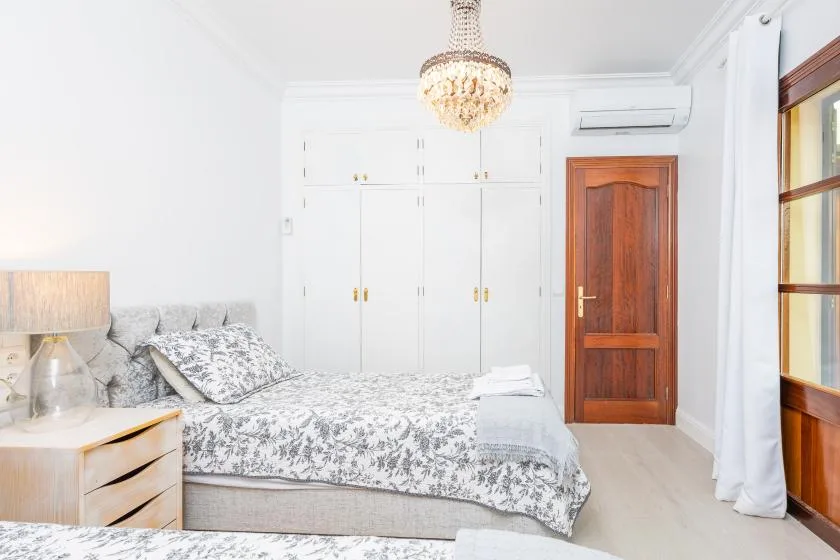 Un dormitorio luminoso con una colcha estampada y una puerta de madera.