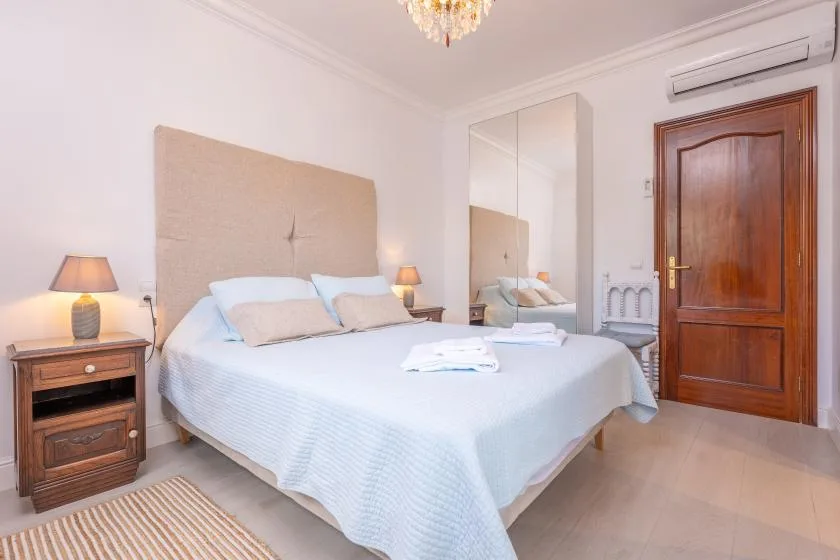 Un dormitorio con una cama grande, mesitas de noche y un armario con espejo.