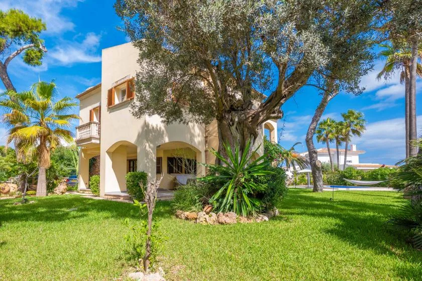 Una villa se alza entre árboles y un césped verde.
