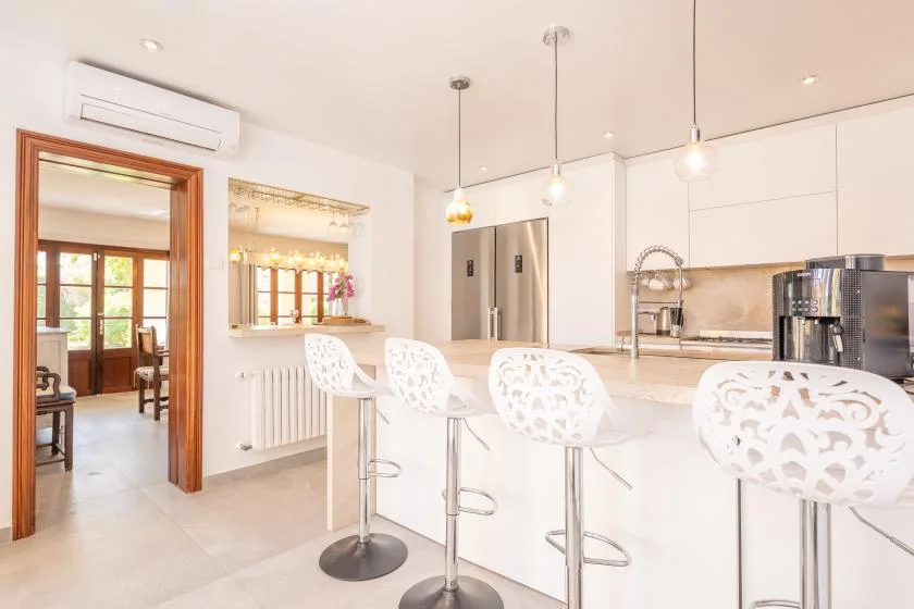 Una cocina luminosa con una isla blanca y un comedor contiguo.
