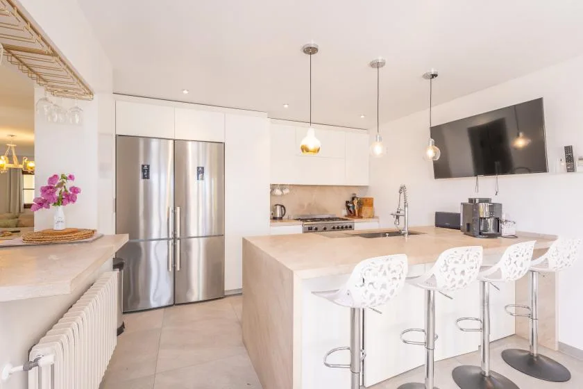 Una cocina moderna y luminosa con una isla grande y electrodomésticos de acero inoxidable.