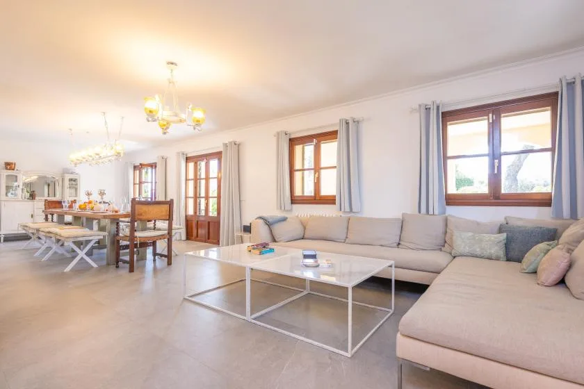 Una sala luminosa con un sofá seccional y una mesa de centro de vidrio.