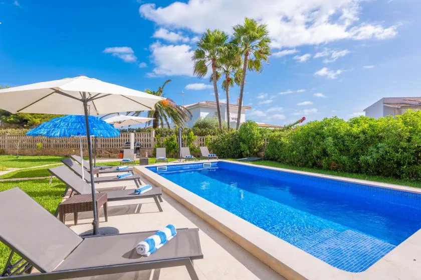 Una piscina al aire libre junto a tumbonas y grandes sombrillas.