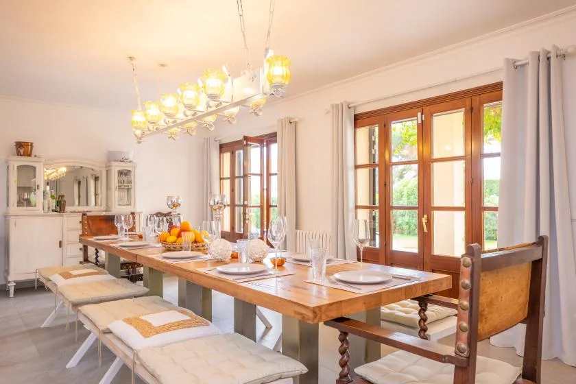 Un comedor luminoso con una larga mesa de madera junto a grandes ventanas.
