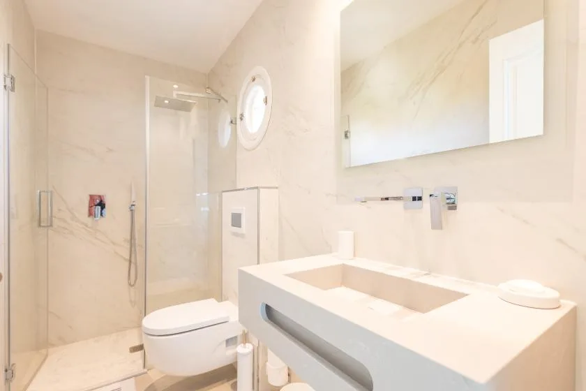 Un baño luminoso con ducha de vidrio, inodoro y una amplia encimera de lavabo.