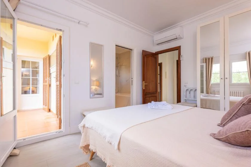 Un dormitorio luminoso con una cama bien arreglada y puertas de armario con espejo.