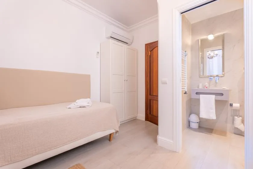 Un dormitorio con una cama y una puerta abierta hacia un baño.