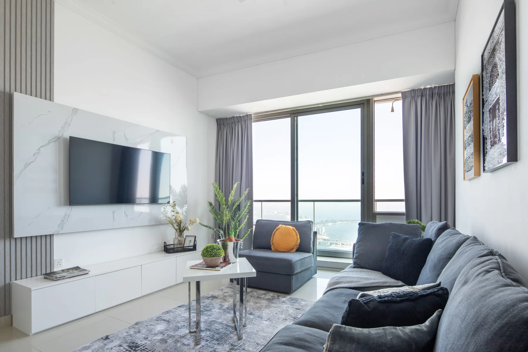A living room with seating, a television, and large windows overlooking the water.