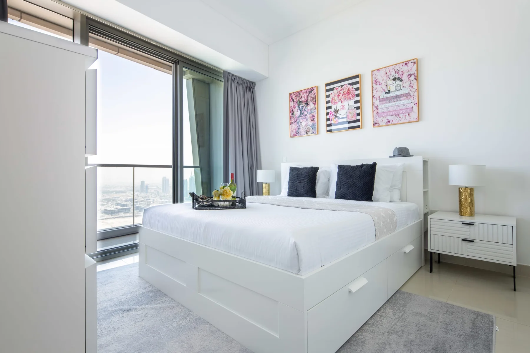 A bright bedroom with a white bed beside a large window.