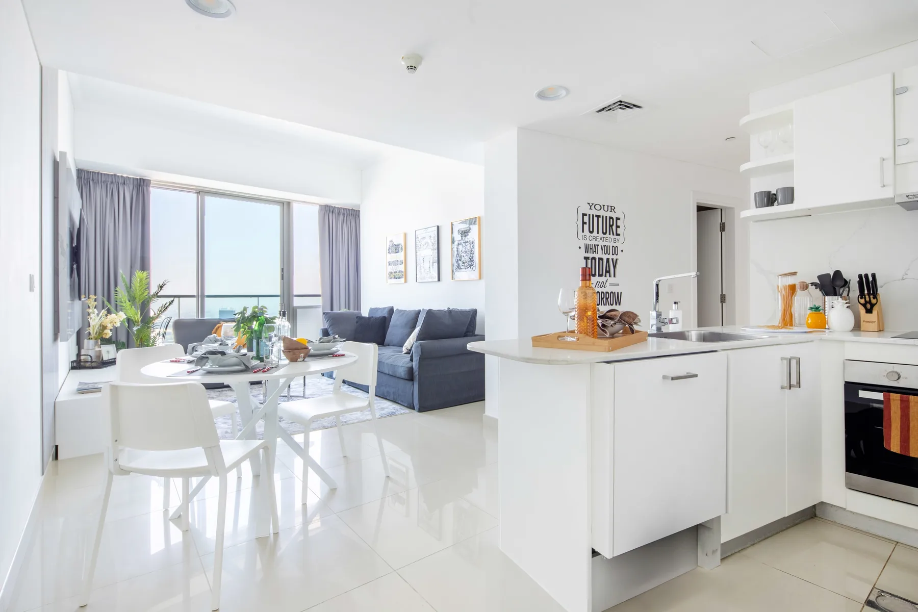 A bright open-plan living area with a dining table, seating, and a kitchen.