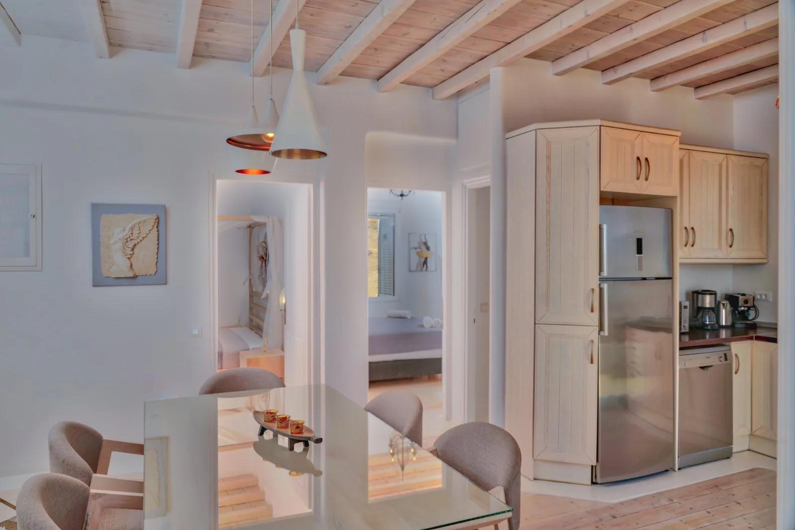 A bright kitchen and dining area with pale wood cabinetry and a glass table.